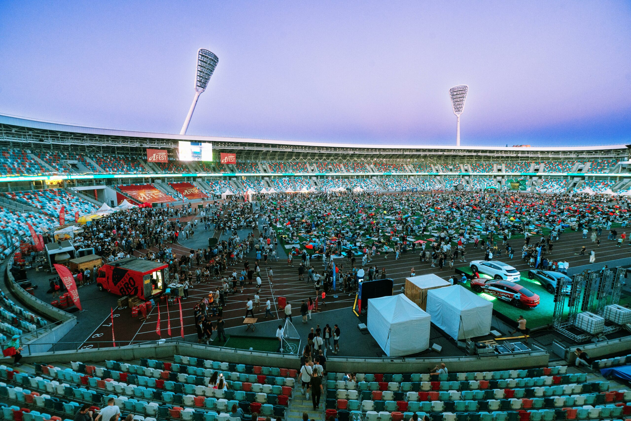 Festival grand public dans un stade avec foule et installations événementielles